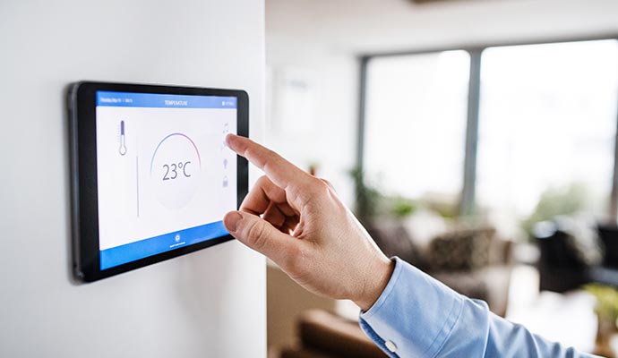 person adjusting smart thermostat temperature