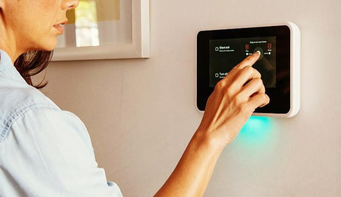 an individual interacting with a home automation system mounted on a wall