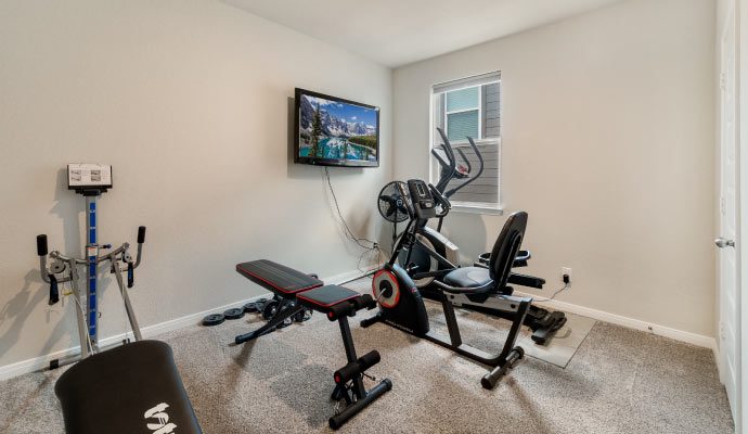 a home gym setup in a room with several pieces of exercise equipment