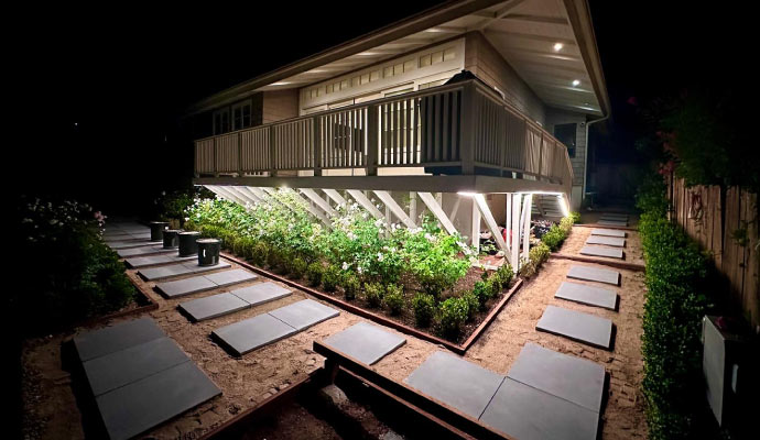 an elevated wooden house at night with outdoor lighting