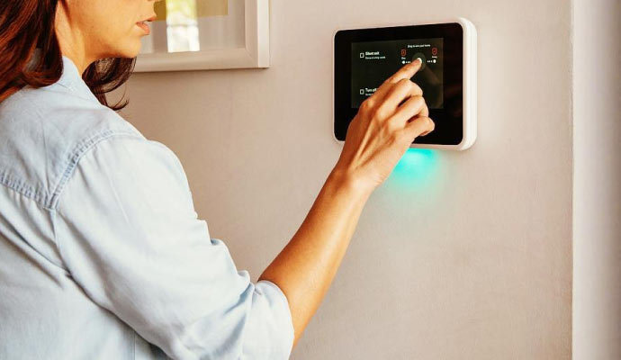 A person using a smart home control panel mounted on the wall